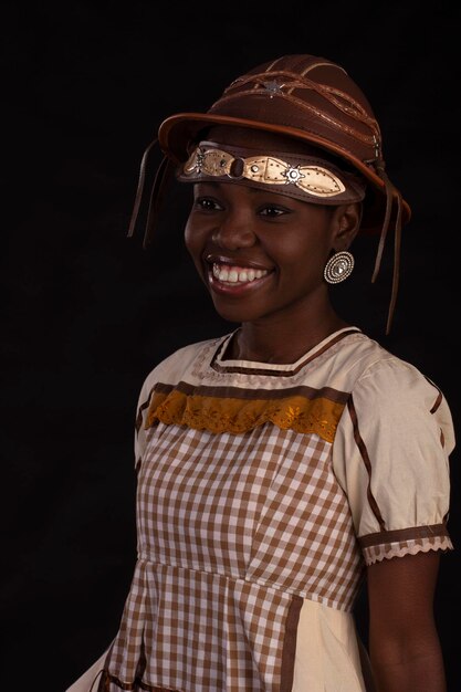 Jeune femme noire portant une robe de soirée de juin avec un chapeau de cancageiro et une photo de studio avec un fond noir Festa Junina