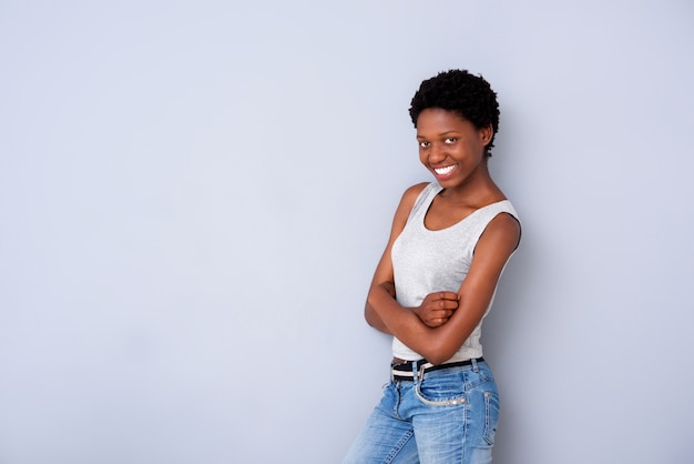 Jeune femme noire posant avec les bras croisés sur le mur gris