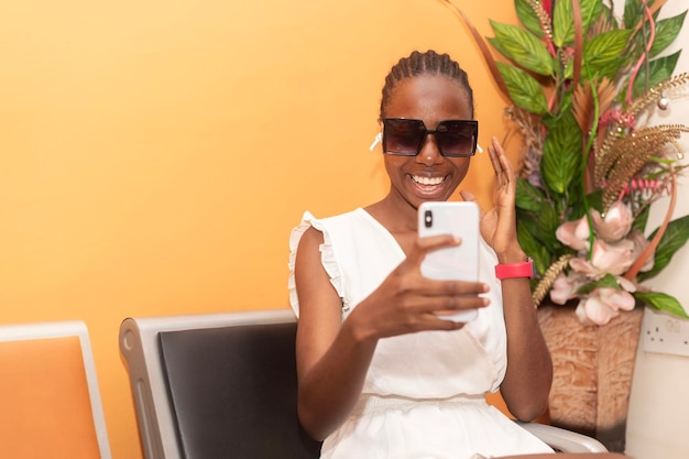 Photo une jeune femme noire qui utilise son téléphone en riant.