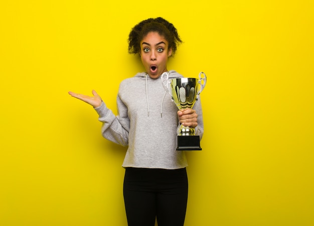 Jeune Femme Noire De Remise En Forme Tenant Quelque Chose Sur La Main De La Paume. Tenant Un Trophée.