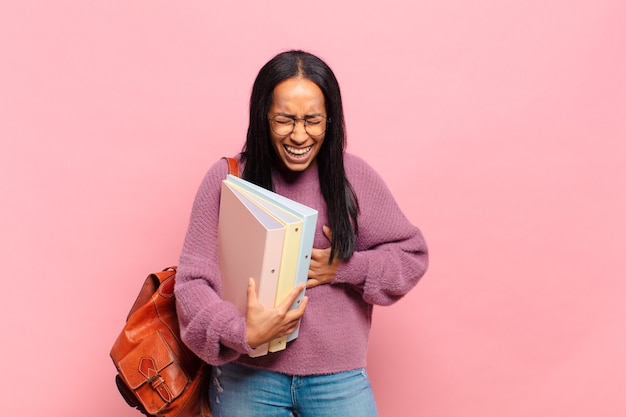 Jeune femme noire riant aux éclats d'une blague hilarante, se sentant heureuse et joyeuse, s'amusant