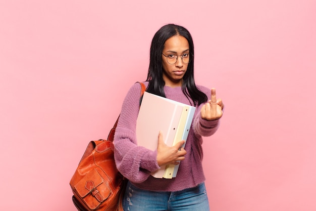 Jeune femme noire se sentant en colère, agacée, rebelle et agressive, renversant le majeur, ripostant. concept d'étudiant