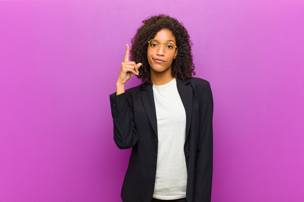 Photo jeune femme noire se sentant comme un génie tenant son doigt dans les airs après avoir réalisé une excellente idée en disant eureka