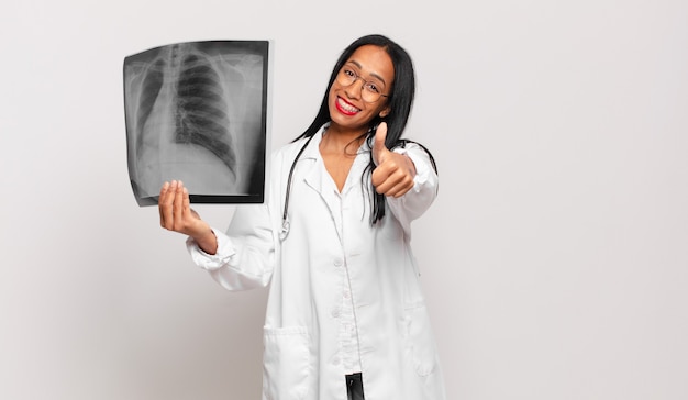 Jeune femme noire se sentant fière, insouciante, confiante et heureuse, souriant positivement avec le pouce levé. concept de médecin