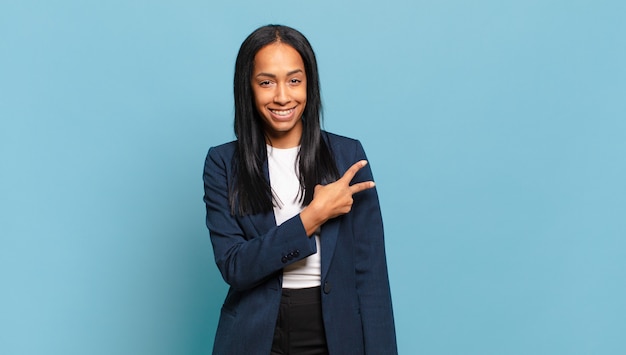 Jeune femme noire se sentant heureuse, positive et réussie, avec une main en forme de v sur la poitrine, montrant la victoire ou la paix. concept d'entreprise