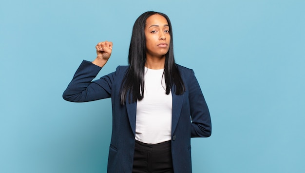 Jeune femme noire se sentant sérieuse, forte et rebelle, levant le poing, protestant ou luttant pour la révolution. concept d'entreprise