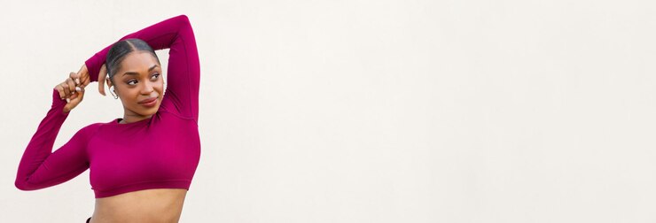 Photo une jeune femme noire sexy et athlétique en vêtements de sport roses posant sur un fond de mur blanc en blanc regardant