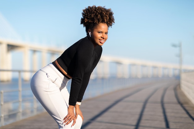 Jeune femme noire sportive prenant une pause pendant l'entraînement en plein air