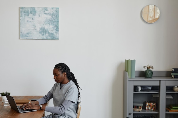 Jeune femme noire en tant qu'infirmière à l'aide d'un ordinateur portable