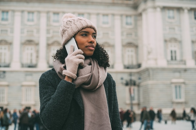 Jeune femme noire sur le téléphone portable près du palais royal en hiver