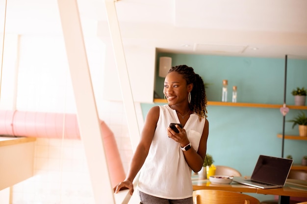 Jeune femme noire utilisant un téléphone portable dans le café