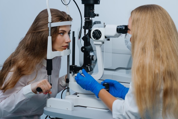 Une jeune femme à la nomination d'un ophtalmologiste Le médecin utilise une lampe à fente pour examiner la vision du patient