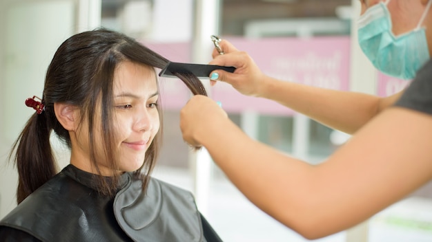 Une jeune femme obtient une coupe de cheveux dans un salon de coiffure, concept de sécurité de salon