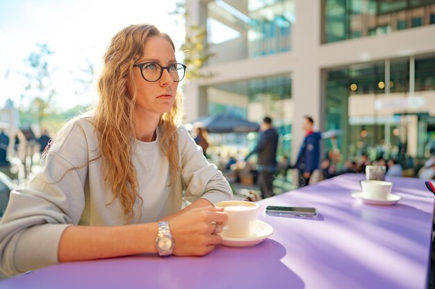 Jeune femme occasionnelle s'asseyant à la table dans le coffeeshop