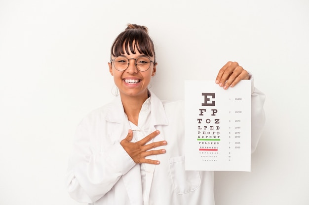 Jeune femme opticienne métisse faisant un test isolé sur fond blanc en riant et en s'amusant.