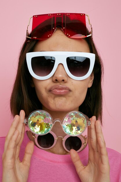 Jeune femme optimiste beaucoup de lunettes sur le visage dans un fond isolé de t-shirt rose