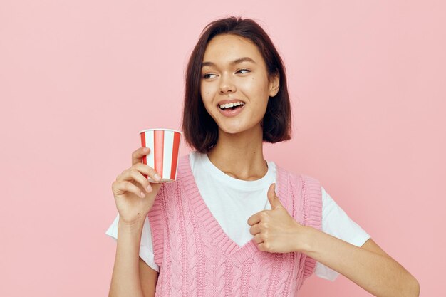 Jeune femme optimiste verre à boire jetable dans un T-shirt rose Style de vie inchangé