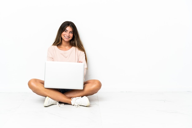 Jeune femme avec un ordinateur portable assis sur le sol isolé