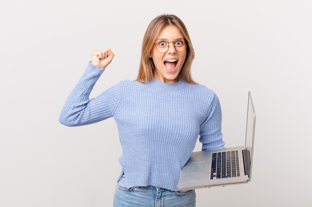 Jeune femme avec un ordinateur portable criant agressivement avec une expression de colère