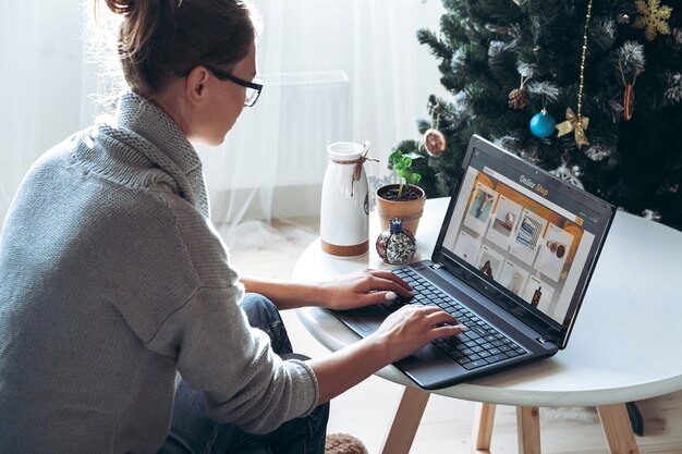 Jeune femme avec ordinateur portable sur le fond d'un arbre de Noël