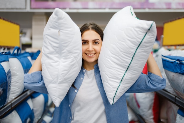 Photo jeune femme avec des oreillers en magasin de linge de lit
