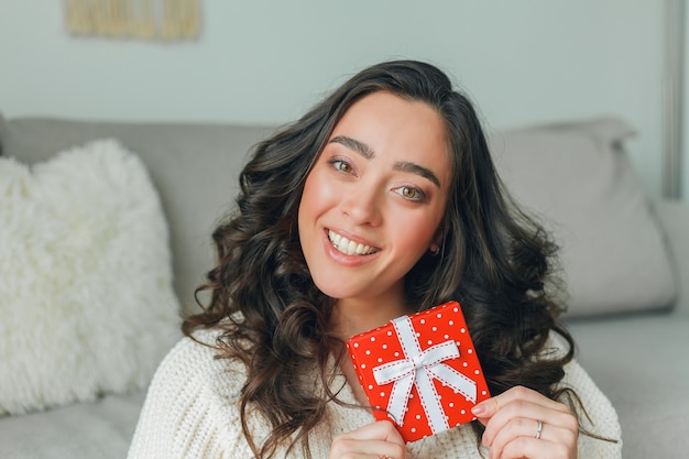 Jeune femme ouvre une boîte cadeau rouge