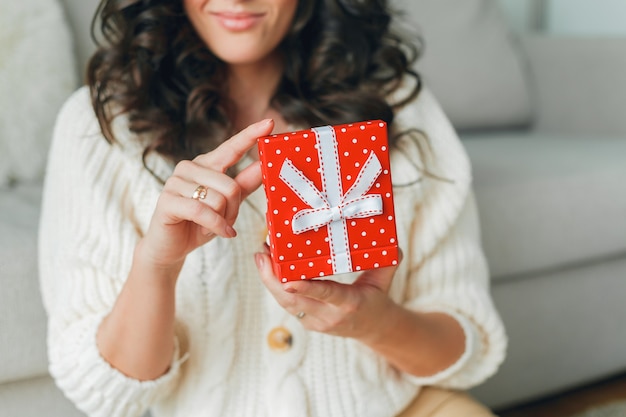 Jeune femme ouvre une boîte cadeau rouge