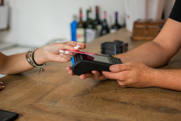 Une jeune femme paie avec une carte de crédit dans un pub.