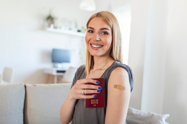 Jeune femme avec un pansement adhésif sur le bras après le vaccin contre le virus Corona covid 19 tenant son passeport. prêt à voyager. Premiers secours. Concept médical, pharmaceutique et de soins de santé.