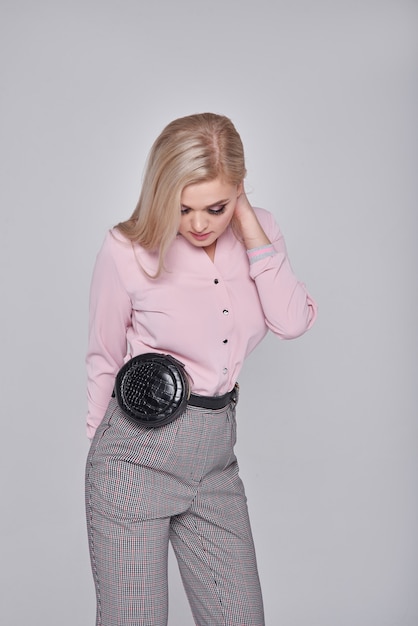 jeune femme en pantalon et une chemise rose. Fille posant sur un mur gris. coiffure. Fille avec un sac à main noir dans un train. Photo de mode