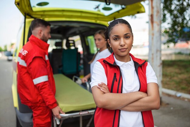 Jeune femme paramédicale afro-américaine debout à l'arrière de l'ambulance paramédic près de l'ambulance