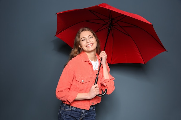 Jeune femme, à, parapluie rouge, sur, arrière-plan couleur