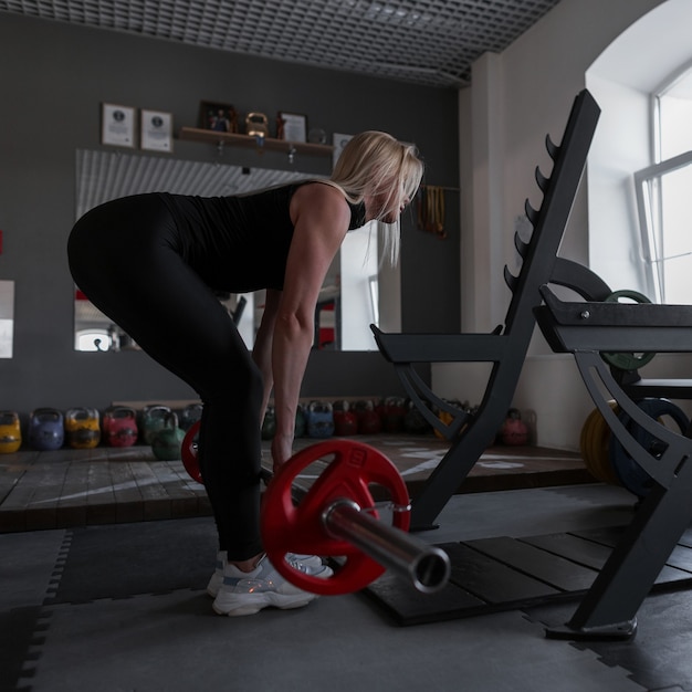 Une Jeune Femme Parfaite Avec Un Corps Sportif Fait Des Exercices Avec Une Barre Dans La Salle De Gym