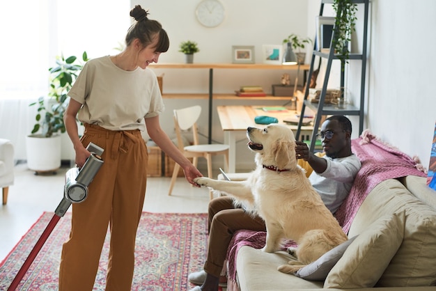 Jeune femme parlant au chien pendant ses travaux ménagers à la maison