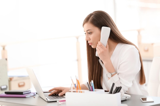 Jeune femme parlant au téléphone sur le lieu de travail