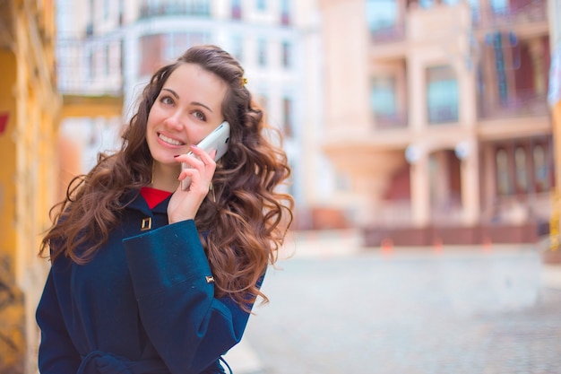 Jeune femme parlant au téléphone, smartphone dans la rue.