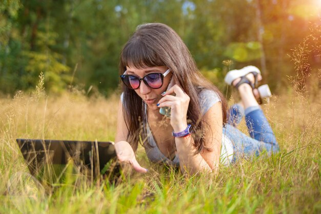 Jeune femme parlant émotionnellement au téléphone et regardant un ordinateur portable indépendant travaille dans un