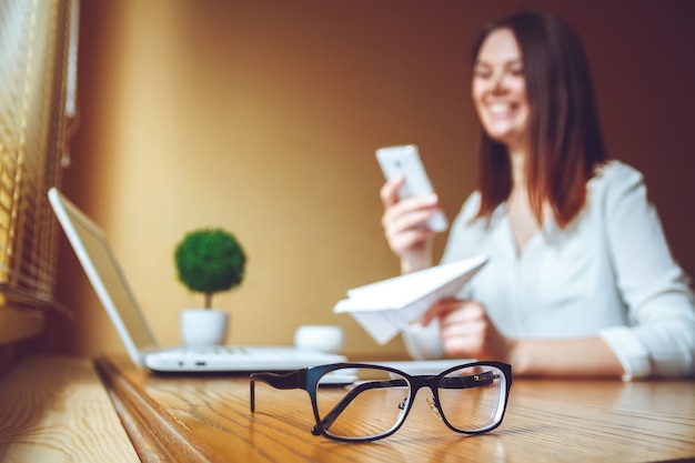 Jeune femme parlant par téléphone alors qu'il était assis sur le lieu de travail