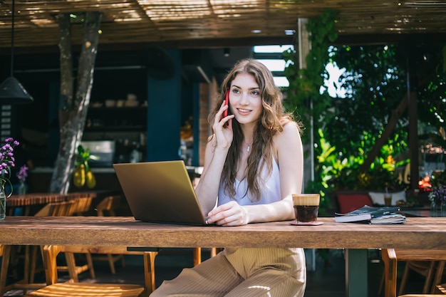 Jeune femme parlant sur smartphone au café en plein air