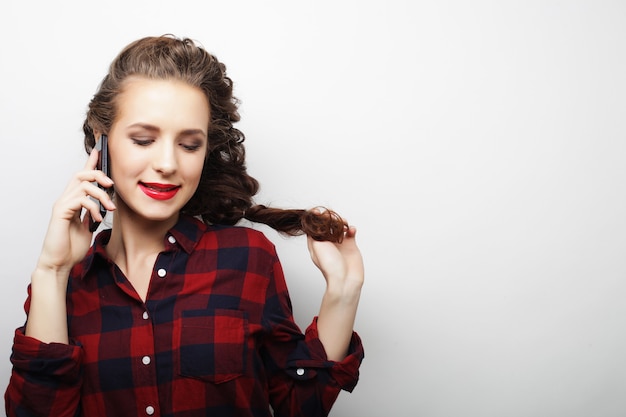 Jeune femme parlant sur smartphone sur fond blanc