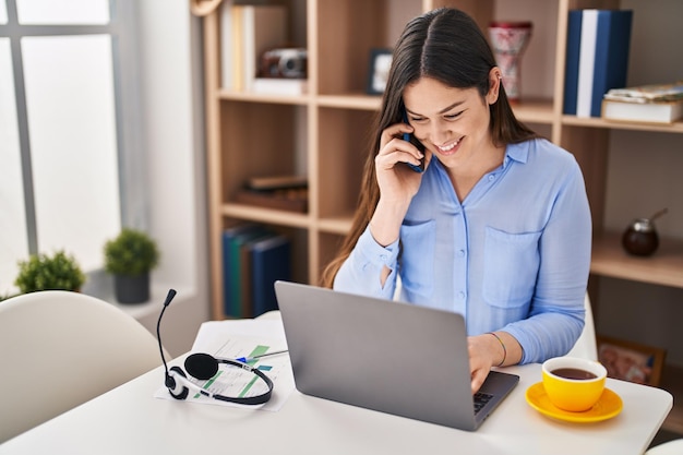 Jeune femme parlant sur le smartphone travaillant à la maison