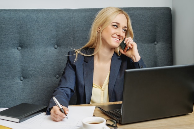 Jeune femme parle par téléphone portable au bureau.