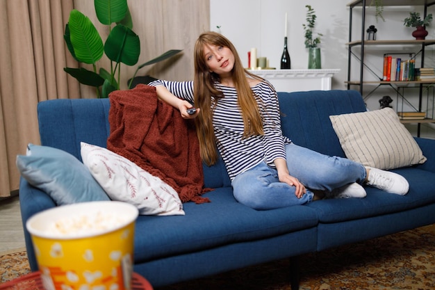 Jeune femme passe son temps libre à regarder la télévision sur le canapé à la maison