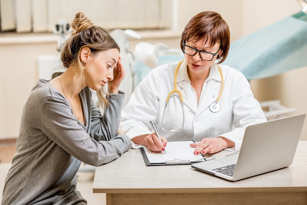 Jeune femme patiente avec un gynécologue senior lors de la consultation au bureau