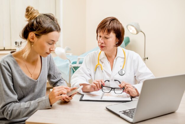 Jeune femme patiente avec un gynécologue senior lors de la consultation au bureau