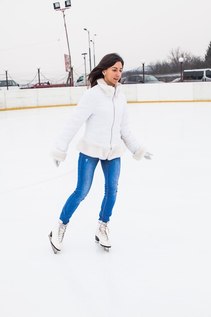 La jeune femme patine sur la patinoire, l'hiver se détend