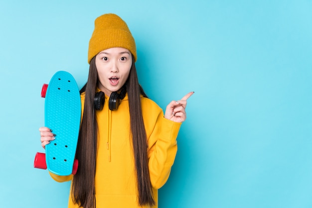 Jeune femme patineuse chinoise isolée pointant vers le côté