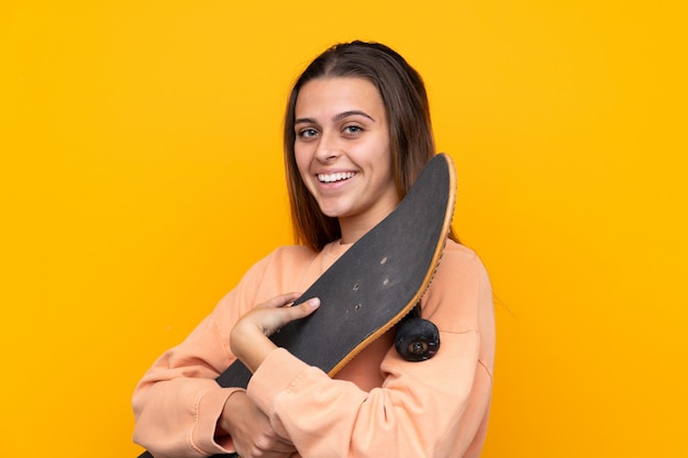 Jeune femme patineuse sur mur jaune isolé