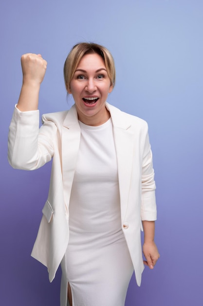 Jeune femme patron blonde soignée joyeuse dans une veste et une robe blanches