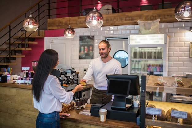 Jeune femme payant dans une boulangerie